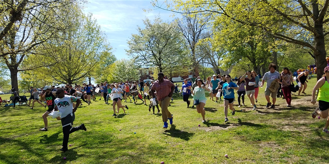 People running down a hill to collect eggs during the Adult Egg Hunt at Dix Park