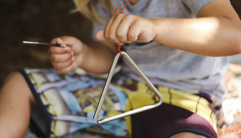Child playing triangle instrument