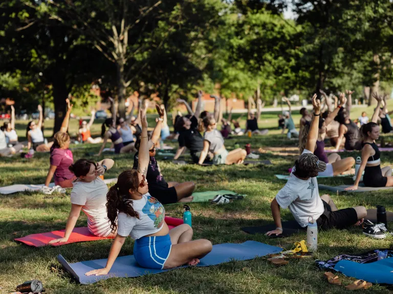 people seated doing yoga in the grass