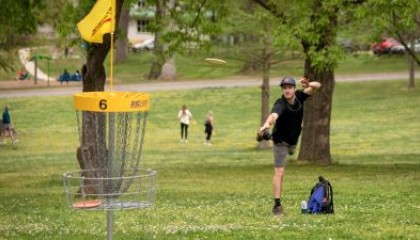 Disc golfer puts into a basket at Dix Park